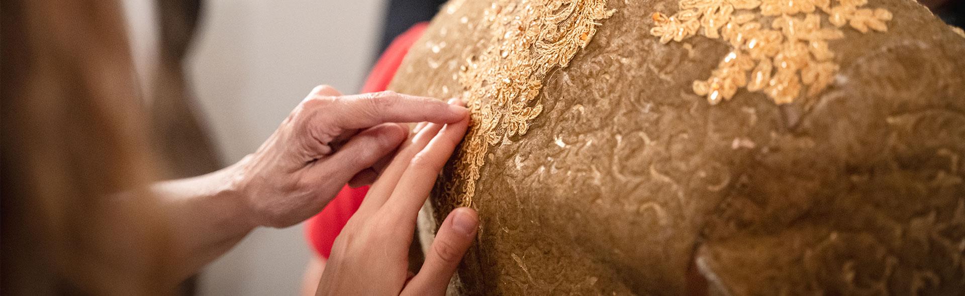 © Marta Cervone Dettaglio di due mani che toccano un costume dello spettacolo “Il barone rampante” di Italo Calvino, diretto dal regista Riccardo Frati. Il costume è dorato, in stile settecentesco, con decorazioni floreali e piccole pietre.